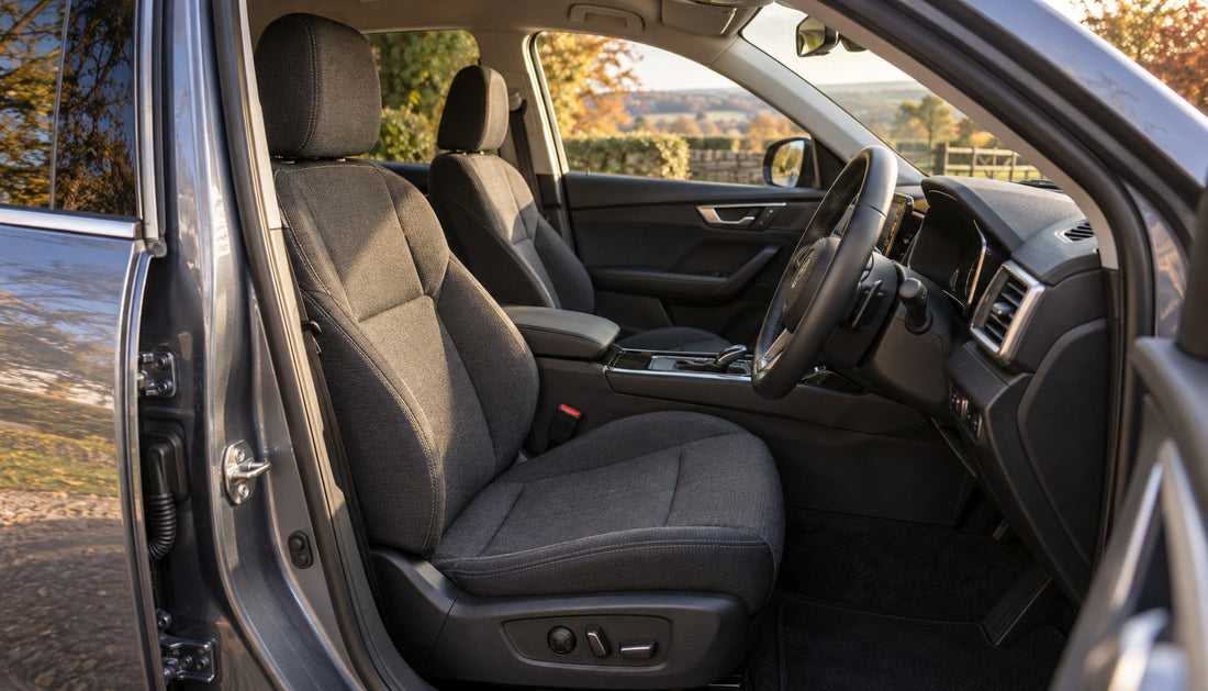 Driver's seat and adjustment controls in a parked right-hand-drive car, seen through the open door.